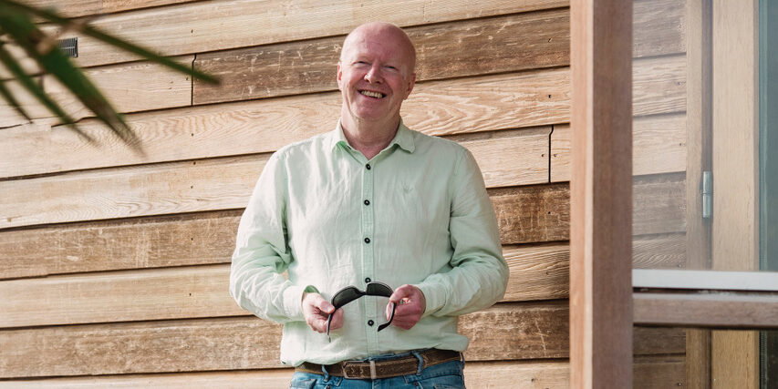 Bert Maalderink staand voor houten muur Bert Maalderink